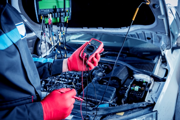 自動車整備士は、電圧計を使用して電圧レベルをチェックします。
