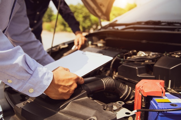 Auto mechanic using checklist for car engine systems after fixed.