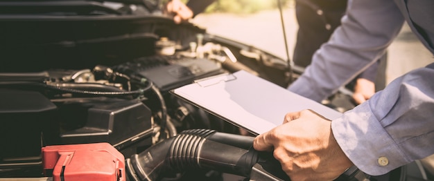 Auto mechanic using checklist for car engine systems after fixed