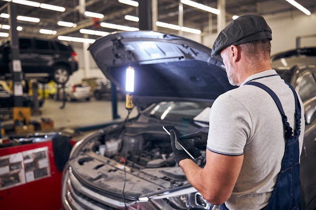 Auto mechanic using tablet computer at auto repair station