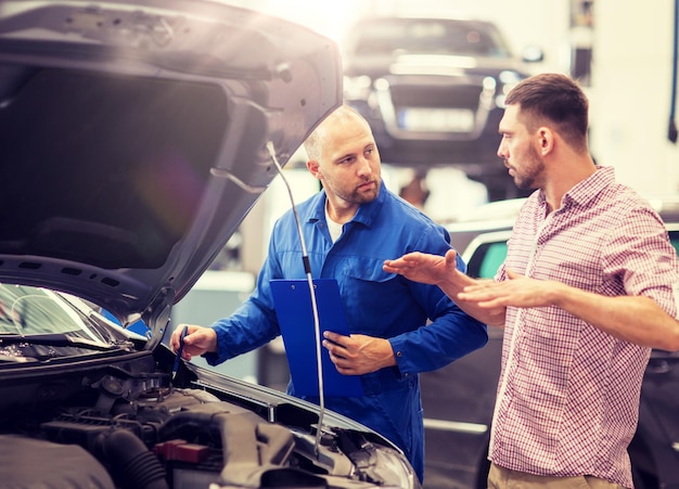 Foto meccanico auto con clipboard e uomo al negozio di auto