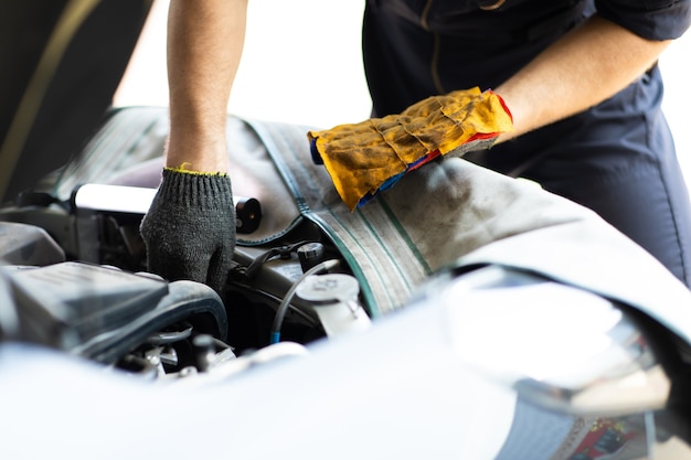 Operaio meccanico automatico che controlla il livello dell'olio nel motore dell'auto. manutenzione auto e concetto di garage di servizio auto.