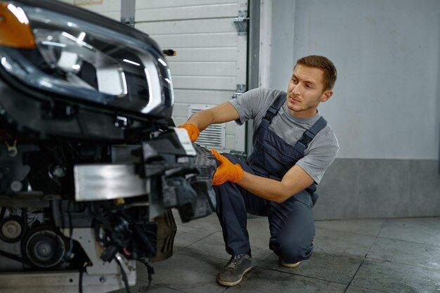 Auto mechanic worker working at car maintenance. Deep car tuning, disassembled vehicle