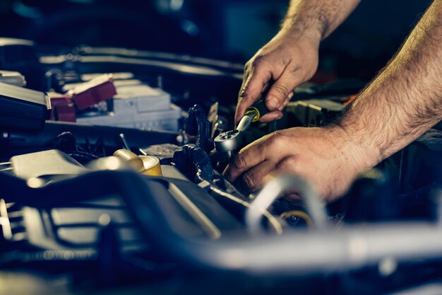 Auto mechanic working on car engine in mechanics garage