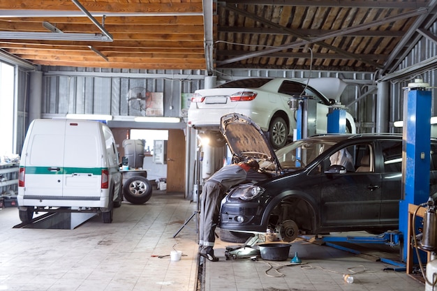 Photo auto mechanic working in garage. repair service.