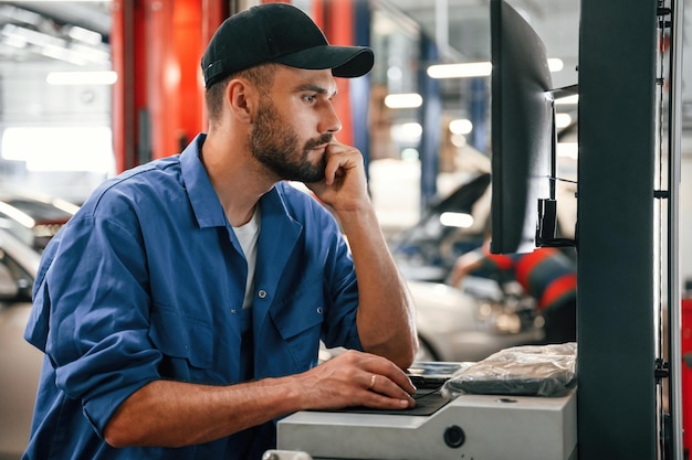 Foto meccanico automobilistico che lavora in garage servizio di riparazione