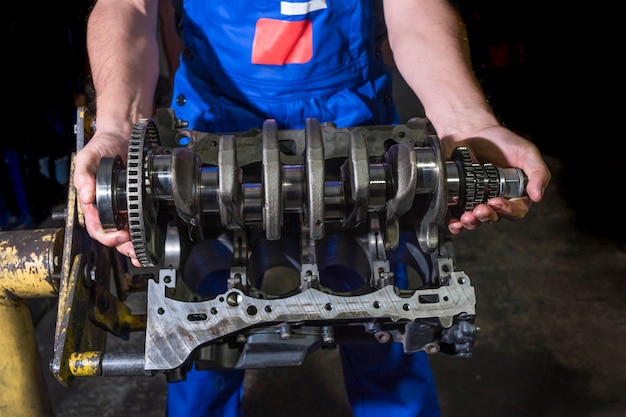 Auto mechanic working in a garage with a disassembled engine