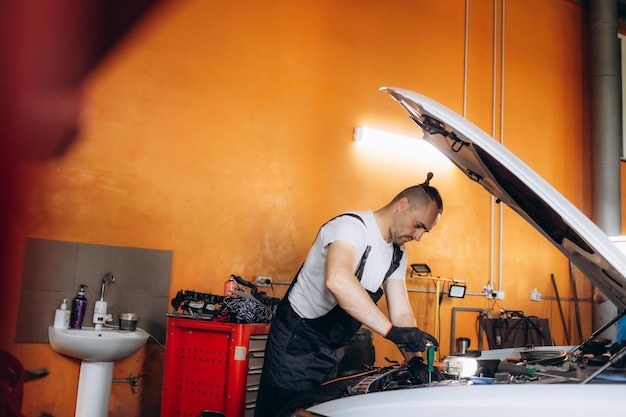 Auto mechanic working under the hood in garage