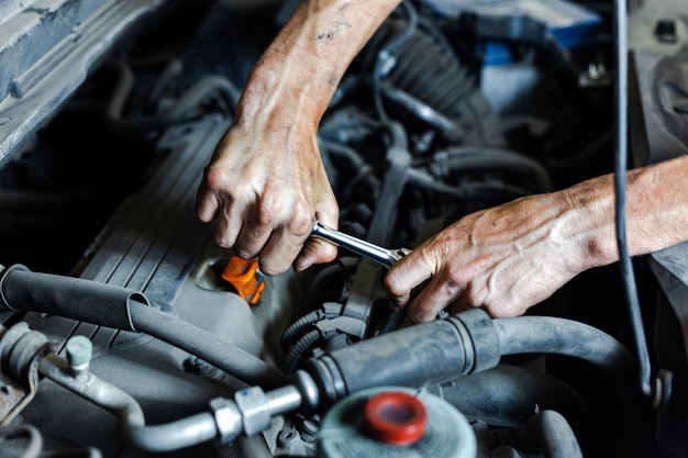 An auto mechanic works with a car engine in the mechanics' garage Car repair closeup