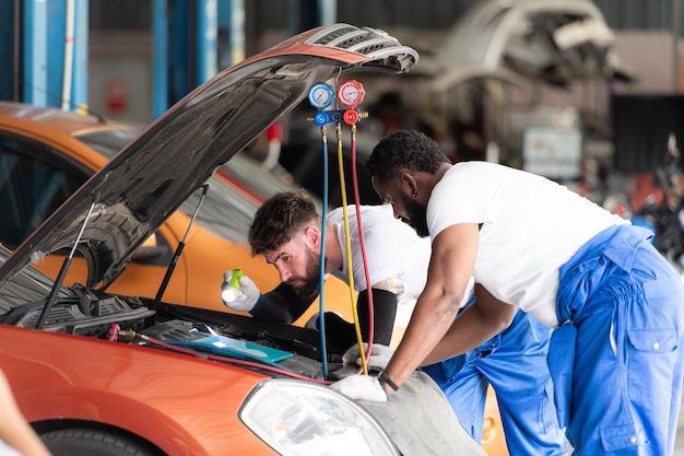 Auto-mechanicus die in een auto-reparatiewerkplaats werkt en de werking van de airconditioner van de auto inspecteert