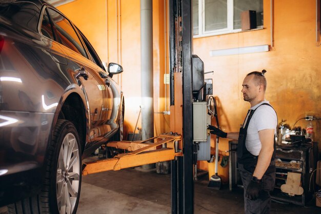 auto-mechanicus met sleutel spannen auto ophanging detail van opgeheven auto op reparatie service station