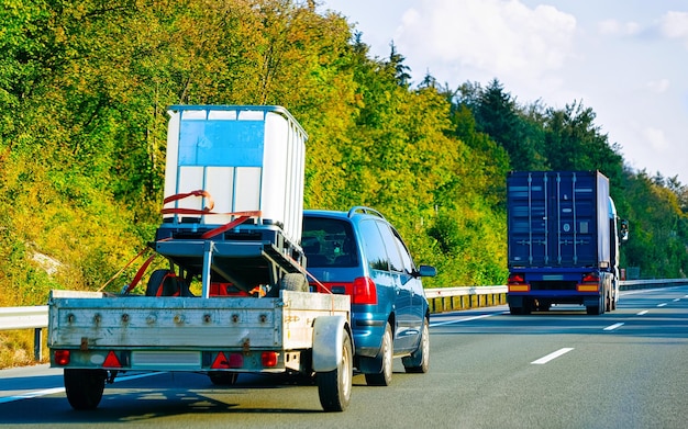 Auto met aanhanger in de weg. auto voertuigen met vervoerder vervoerder vervoerder op oprit. europese transportlogistiek bij werktransport. trekken met chauffeur op snelweg.