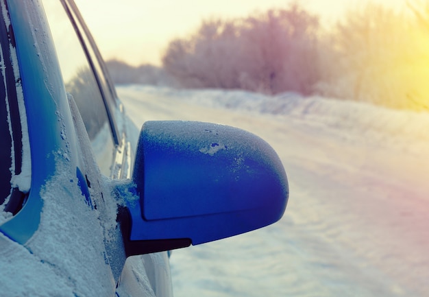 Auto met buitenspiegel. Besneeuwd wegdek