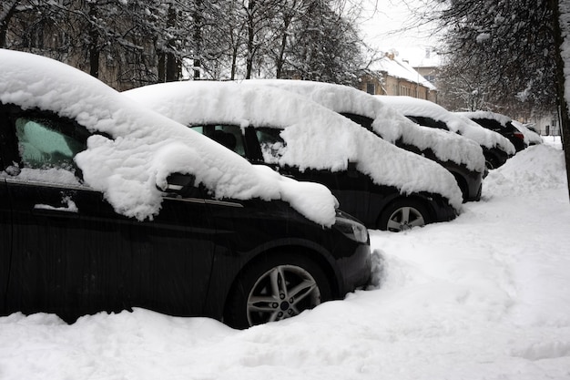 Auto onder dikke deken van sneeuw na storm. voertuigen bedolven onder ijs. niemand