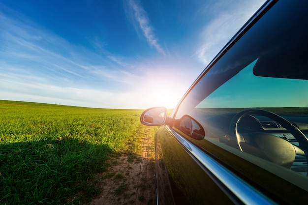 Auto op een onverharde weg in een veld met zonnebloemen en tarwe met zonlicht