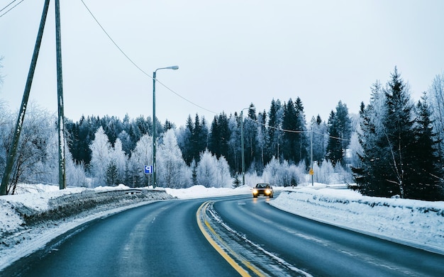 Auto op Winterweg met sneeuw in Finland. Auto en koud landschap van Lapland. Auto op het bos van Europa. Finse stad snelweg rit. Rijbaan en route besneeuwde straat trip. Het rijden