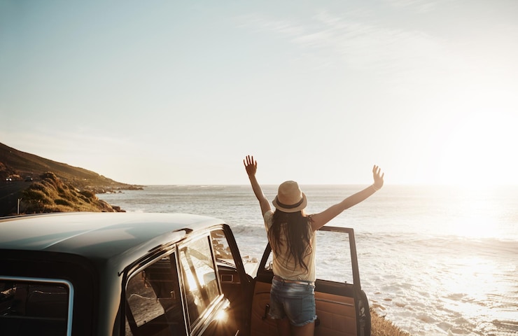Foto auto reizen en vrouw met vrijheid op het strand voor zomervakantie sightseeing en uitzicht op zonsondergang reis rijden en persoon door de oceaan op road trip voor avontuur viering en toerisme in californië