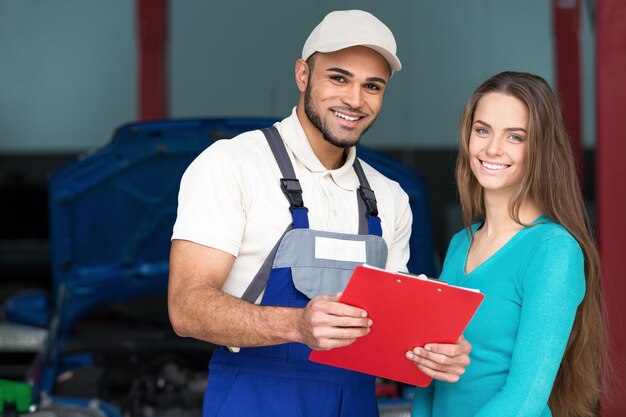 Officina riparazioni auto, meccanico maschio e cliente femminile vicino auto