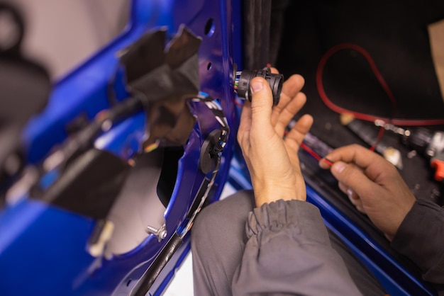 Auto repair technicians in car repair shops are repairing car door systems and repairing electric vehicle systems.