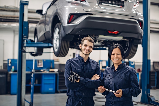 Auto reparatie centrum. Twee gelukkige werktuigkundigen - man en vrouw die zich door de auto bevinden