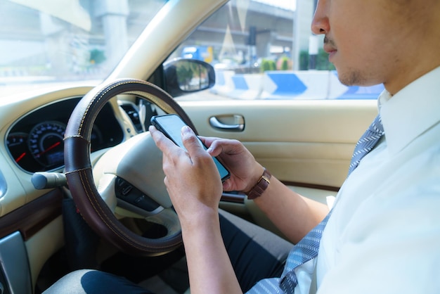 Auto rijden en telefoon gebruiken. Afgeleide bestuurder sms't met mobiele telefoon. Onverantwoordelijke man die bericht controleert met smartphone in het verkeer. Auto-ongeluk concept. Slim apparaat in de hand houden.