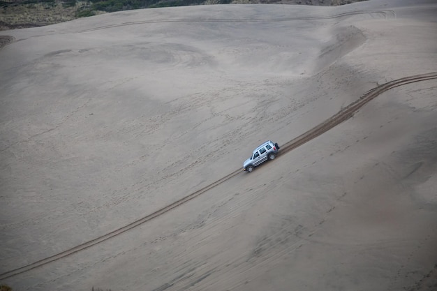 Auto rijdt de steile heuvel af op een zandstrand