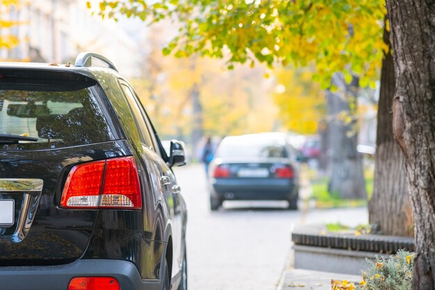 Auto's geparkeerd op een rij aan de straatkant van een stad op een heldere herfstdag.