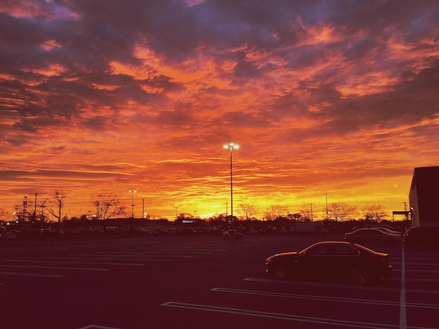 Foto auto's op de parkeerplaats tegen de dramatische hemel tijdens de zonsondergang