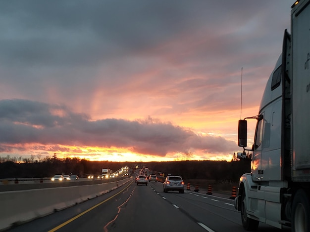 Foto auto's op de weg tegen de dramatische hemel tijdens zonsondergang