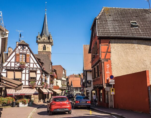 Auto's op straat te midden van gebouwen en een kerktoren tegen een heldere lucht