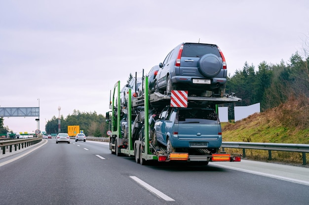 Auto's vervoerder vervoerder vrachtwagen in de weg. Auto voertuigen vervoerder op oprit. Europese transportlogistiek bij werktransport. Zware aanhanger met chauffeur op snelweg.