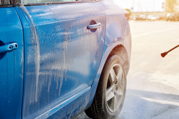 Auto schoonmaken met water onder hoge druk bij wasstraat