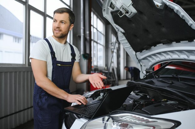 Auto service repair maintenance concept mechanic checks the car making diagnostics with laptop at the service station service maintenance of industrial to engine repair