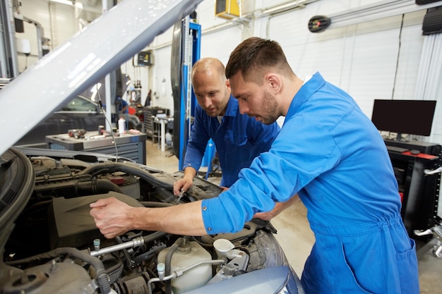 Foto servizio auto, riparazione, manutenzione e concetto di persone - meccanici con chiave inglese che riparano auto in officina