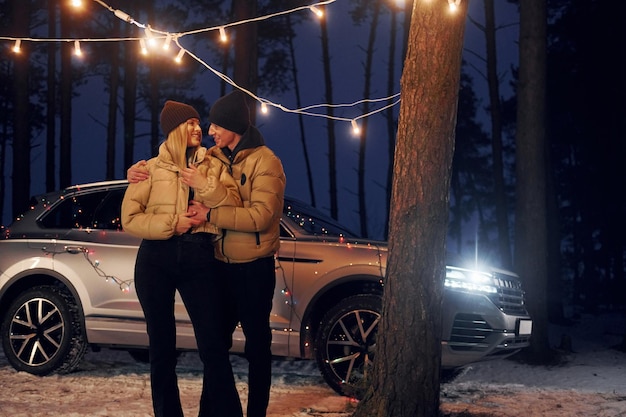 Auto staat op de achtergrond Koppel staat in het bos en viert Nieuwjaar