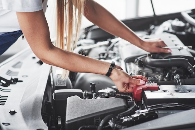 Auto verslaafde vrouw repareert overdag zwarte auto binnenshuis in de garage