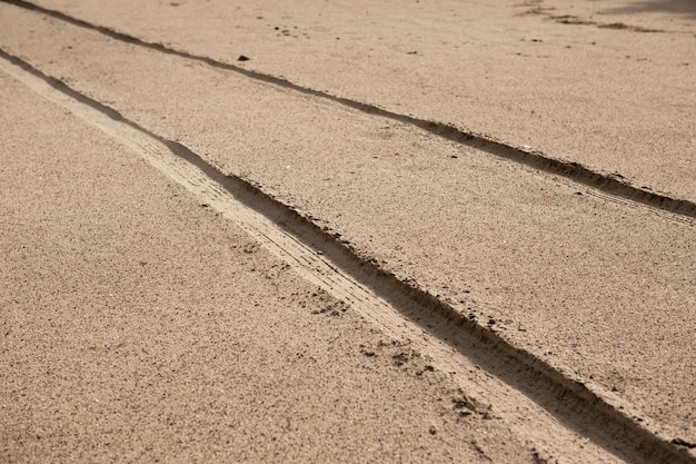 Autobandsporen op het strandzand in perspectief.