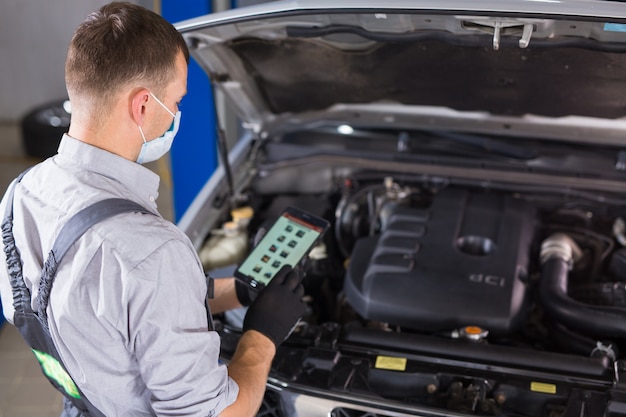 Autodienstmedewerker voert diagnostiek en autoreparaties uit in de kamer.