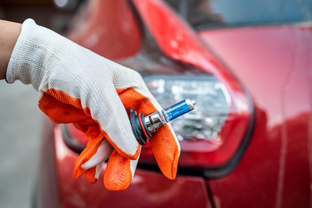 Autolamp in een hand op de achtergrond van een autokoplamp