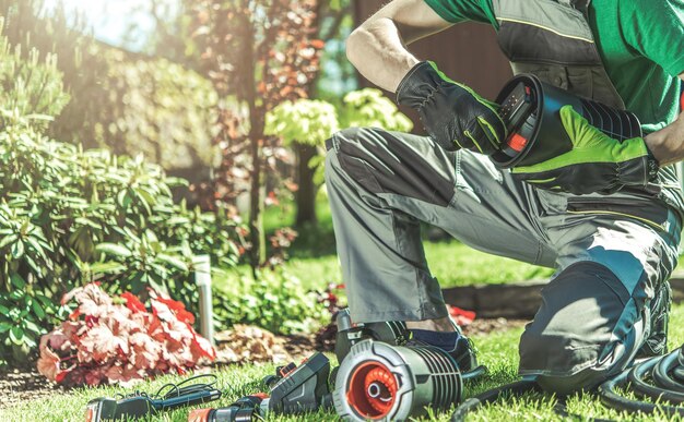 Photo automatic backyard garden watering system installation performed by professional caucasian garden technician automatic lawn sprinklers