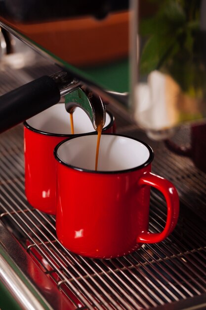 Automatic coffee machine makes two espresso coffee in red vintage cups