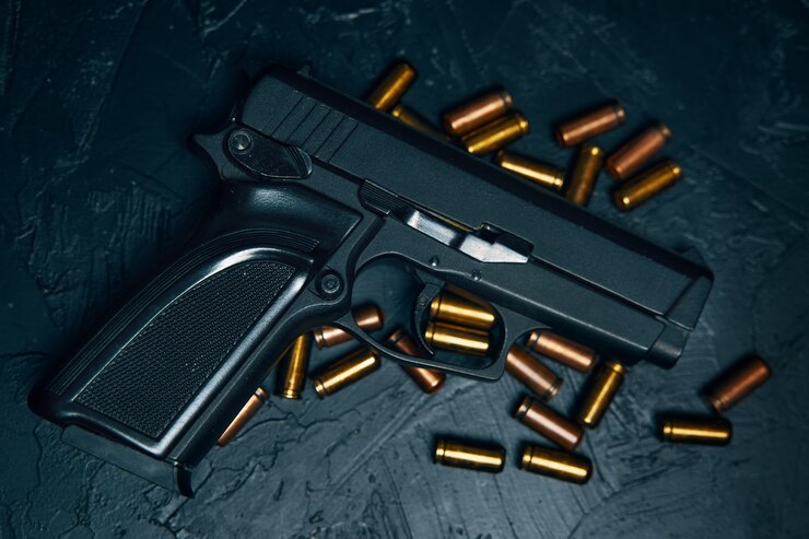 Automatic firearms with bullets black pistol with cartridges on table weapons on concrete background...