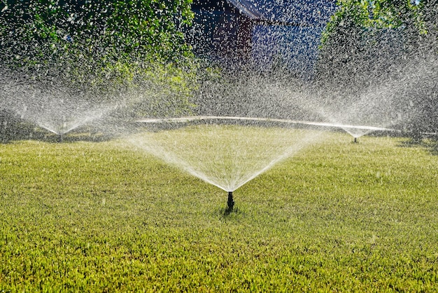 Foto tecnologia di irrigazione del cortile con irrigatore automatico da giardino per prato verde