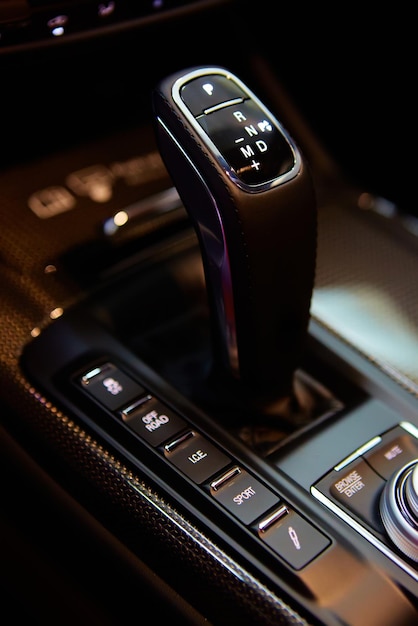 Automatic gear stick of a modern car, multimedia and navigation\
control buttons. car interior details. transmission shift. shallow\
dof.