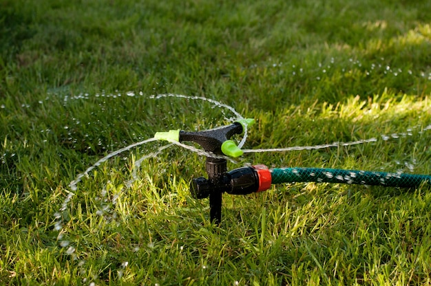 Automatic watering machine for plants on the background of a green lawn