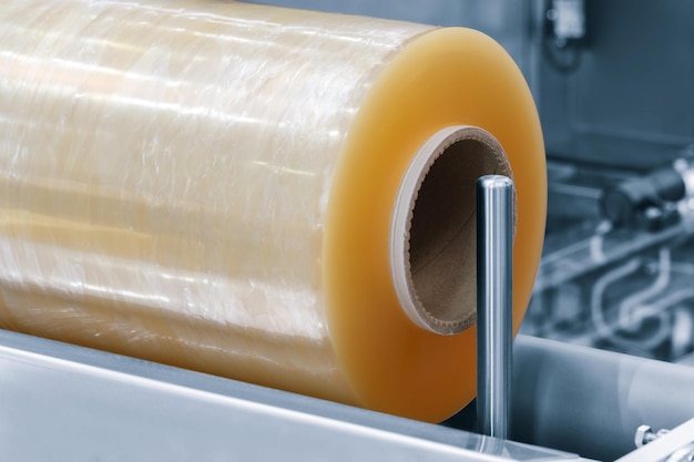 Automatische machine voor de productie van polyethyleenplasticzakken met verlichtingseffect Close-up van de rol van de plasticzakkenproductiemachine in de lichtblauwe scène productverpakkingsconcept