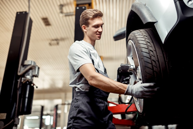 An automechanic changes a tire while at work at a car repair service.