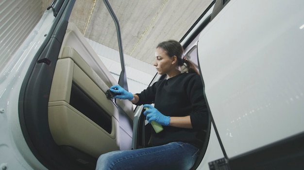 Automobile cleaning  attractive young woman is washing car door of a luxury vehicle