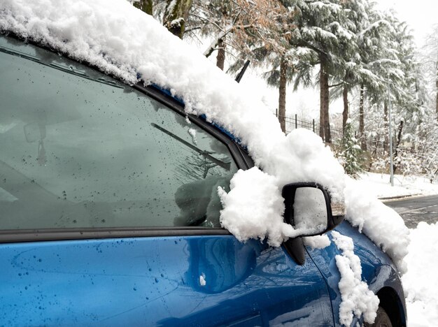 雪の吹きだまり後の冬の日に雪に覆われた自動車