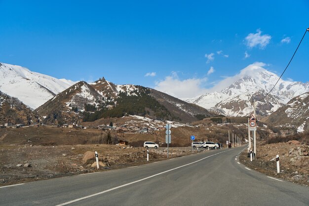 Automobile mountain road to the bottom of mount kazbegi. snow cap on the top of the mountain